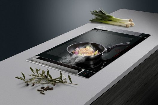 Elegantes Duo: 80 cm breite flexible Induktion mit zwei nahezu unsichtbaren Muldenlüftungen rechts und links davon. Bei Inbetriebnahme öffnen sich die Lüftungsklappen, um die Kochschwaden effizient nach unten abzusaugen. (Bild: © AMK)